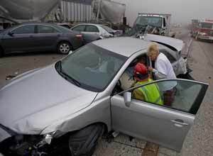 AP Photo/Eric ReedRegistered Nurse Stacy Blevins and EMS personnel attend to injured passengers after a multi-vehicle collision in the heavy fog at the Cajon Pass on Interstate 15 near Oak Hills, Calif., on Wednesday.