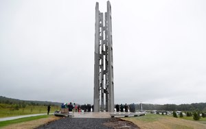 In this Sept. 9, 2018 file photo, people attending the dedication stand around the 93-foot tall Tower of Voices at the Flight 93 National Memorial in Shanksville, Pa., where the tower contains 40 wind chimes representing the 40 people that perished in the crash of Flight 93. (AP Photo/Keith Srakocic, Pool, File)
