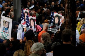People hold up photo memorials during a ceremony marking the 17th anniversary of the terrorist attacks on the United States on Tuesday, Sept. 11, 2018, in New York. (AP Photo/Mark Lennihan)