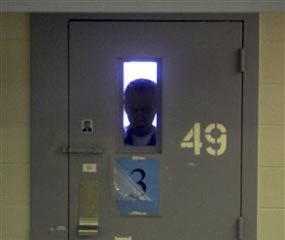 A mentally ill man is silhouetted by his cell's window as he peers out from the small opening of his cell door inside Idaho's maximum security prison south of Boise, Idaho, Jan. 24, 2007. He is one of many of Idaho's mentally ill sent to the prison for treatment because there is no where else for him to go. He is too sick to be treated as an outpatient and too dangerous for lower-level security hospitals.