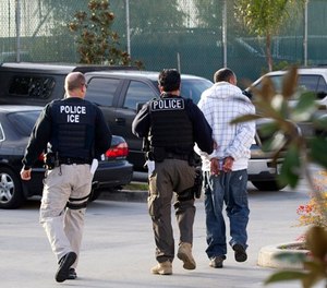 In this March 30, 2012, file photo, Immigration and Customs Enforcement agents take a suspect into custody as part of a nationwide immigration sweep in Chula Vista, Calif. (AP Photo/Gregory Bull, File)