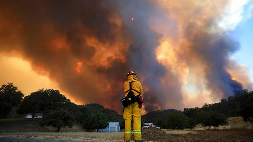 A firefighter runs while trying to save a home as a wildfire tears through Lakeport, Calif.