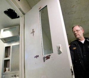 Yakima County Jail spokesman Cpl. Ken Rink shuts the door of the cell number 10 Saturday, Nov. 26, 2005, from which nine inmates escaped Friday night after punching the hole through the ceiling and climbing up onto the facility's roof.