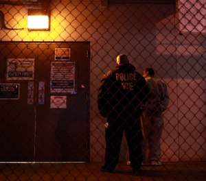 A U.S. Immigration and Customs Enforcement (ICE) officer stands next to a fugitive before entering a staging facility in Los Angeles, Wednesday, Dec. 9, 2009. (AP Photo/Jae C. Hong)
