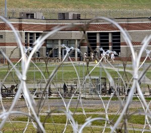 In this Tuesday, July 3, 2012 photo, inmates walk in the yard in front of a cellblock at the maximum-security Mount Olive Correctional Center in Mount Olive, W.Va.