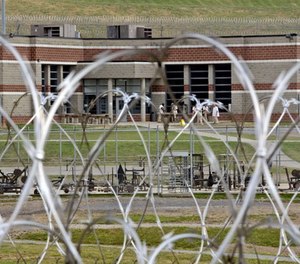 In this Tuesday, July 3, 2012 photo, inmates walk in the yard in front of a cellblock at the maximum-security Mount Olive Correctional Center in Mount Olive, W.Va.