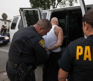 Parole and Special Service Unit agents from the California Department of Corrections and Rehabilitation (CDCR) take a parole violator to jail in Los Angeles Wednesday, July 25, 2012. (AP Photo/Damian Dovarganes)