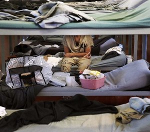 In this June 26, 2014 file photo, a lone inmate in Division 2 Dorm 2 of the Cook County Jail, where male prisoners with mental disorders bunk, sits arms folded on his bunk in Chicago. Cook County plans to open a 24-hour triage center on the far South Side of Chicago where police can drop off people experiencing psychiatric or substance-abuse crises. The goal is ease pressure on the jail, where 1 in 5 detainees is locked up because of mental health problems.