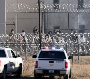 Prisoners burn objects as they mill in a courtyard behind razor wire at the Tecumseh State Correctional Institution in Tecumseh, Neb., Thursday, March 2, 2017. (AP Photo/Nati Harnik)