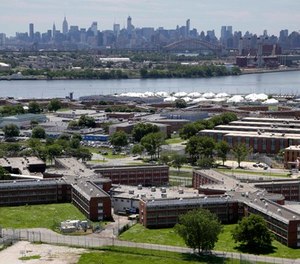 In a June 20, 2014, file photo, the Rikers Island jail complex stands in New York with the Manhattan skyline in the background. (AP Photo/Seth Wenig, File)