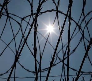 In this Saturday, April 26, 2014 file photo, the sun shines through concertina wire on a fence at the Louisiana State Penitentiary in Angola, La. (AP Photo/Gerald Herbert)