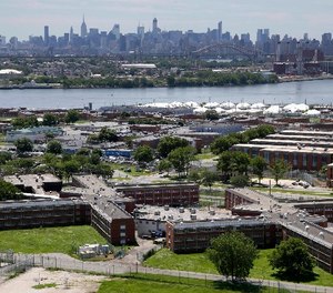 In a June 20, 2014, file photo, the Rikers Island jail complex stands in New York with the Manhattan skyline in the background. (AP Photo/Seth Wenig, File)