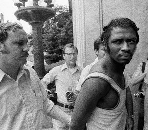 In this Sept. 1, 1973 photo, a federal marshal, left, escorts Herman Bell past members of the media following Bell's capture in New Orleans in connection with the killing of two New York city police officers. (AP Photo)