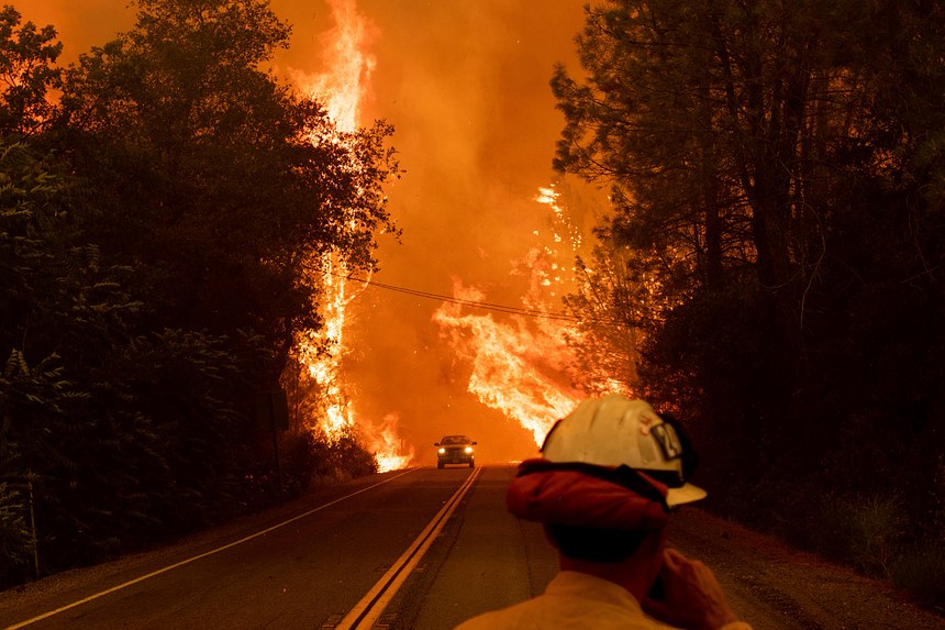 A car passes through flames on Highway 299 as the Carr Fire burns through Shasta, Calif., Thursday, July 26, 2018. Fueled by high temperatures, wind and low humidity, the blaze destroyed multiple homes and at least one historic building. (AP Photo/Noah Berger)