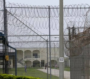 A prisoner works on the lawn at the Dade Correctional Institution on Thursday, July 10, 2014, in Florida City, Fla.