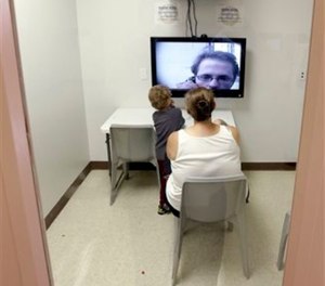 In this photo taken on Tuesday, May 5, 2015, inmate Jesse Cole is shown on a television screen during a video visitation with his family, wife Edna and children William and Jesse James, at the Fort Bend County Jail, in Richmond, Texas.