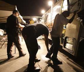 In this file photo, Maricopa County Sheriff's deputies, left, check the shoes of a suspect arrested during a crime suppression sweep in Phoenix. A judge in Arizona on Tuesday, Sept. 18, 2012 ruled that police can immediately start enforcing the most contentious section of the state's immigration law, marking the first time officers can carry out the so-called