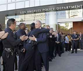 Then-otgoing Los Angeles Police Chief William Bratton and an officer embrace as Bratton exits a ceremony held in his honro at police headquarters in late October 2009. (AP Photo/Reed Saxon)