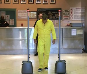 State correctional department spokesman Gerard Shields, wearing a yellow prison jumpsuit, and walks through the Cellsense detector at a demonstration Wednesday.