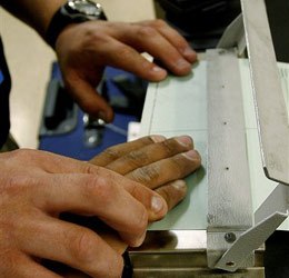 U.S. Immigration and Customs Enforcement (ICE) agent finger prints an alien during an operation Friday, July 14, 2006 in Oklahoma City. (AP photo)