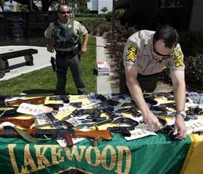 An unidentified Los Angeles County Sheriff's deputy displays weapons confiscated in a gang take down before a news conference Thursday May 21, 2009, in Lakewood, Calif. A Latino street gang waged a racist campaign to eliminate black people from a Southern California city through attempted murders and other crimes, according to federal racketeering indictments. (AP Photo)