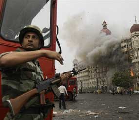 An Indian soldier takes cover as the Taj Mahal hotel burns during gun battle between Indian military and militants inside the hotel in Mumbai, India, Saturday, Nov. 29, 2008. Police said the siege at the Taj Mahal hotel was over after the gun battle, bringing an end to three days of terror in Mumbai in which more than 150 people were killed.