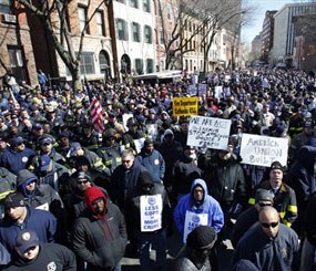 In this March 3, 2011 file photograph, off-duty and retired police officers and firefighters fill a street outside the Statehouse, in Trenton, N.J., during a rally to protest staff cuts and promote public safety. Newark, Trenton, Paterson, Atlantic City and Camden, all densely populated cities with significant crime problems, have made deep cuts in their police departments.