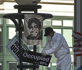 An Oakland public works employee removes signs from a light fixture in Frank Ogawa plaza Monday, Nov. 14, 2011 in downtown Oakland (Calif.). The Occupy encampment was evicted from Frank Ogawa Plaza early this morning. (AP Photo)