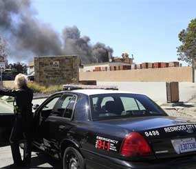 A Redwood City (Calif.) police officer watches as smoke billows from a fire in May 2011. Now that the department has deployed Nixle, city officials wishing to issue a