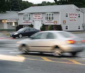 Motorists pass by an alleged brothel at 1550B Post Road, in Warwick, R.I. In April, Warwick police shut down the alleged brothel, a two-story home attached to a cash-for-gold store, but since then it has relocated. (AP Photo/Stew Milne)