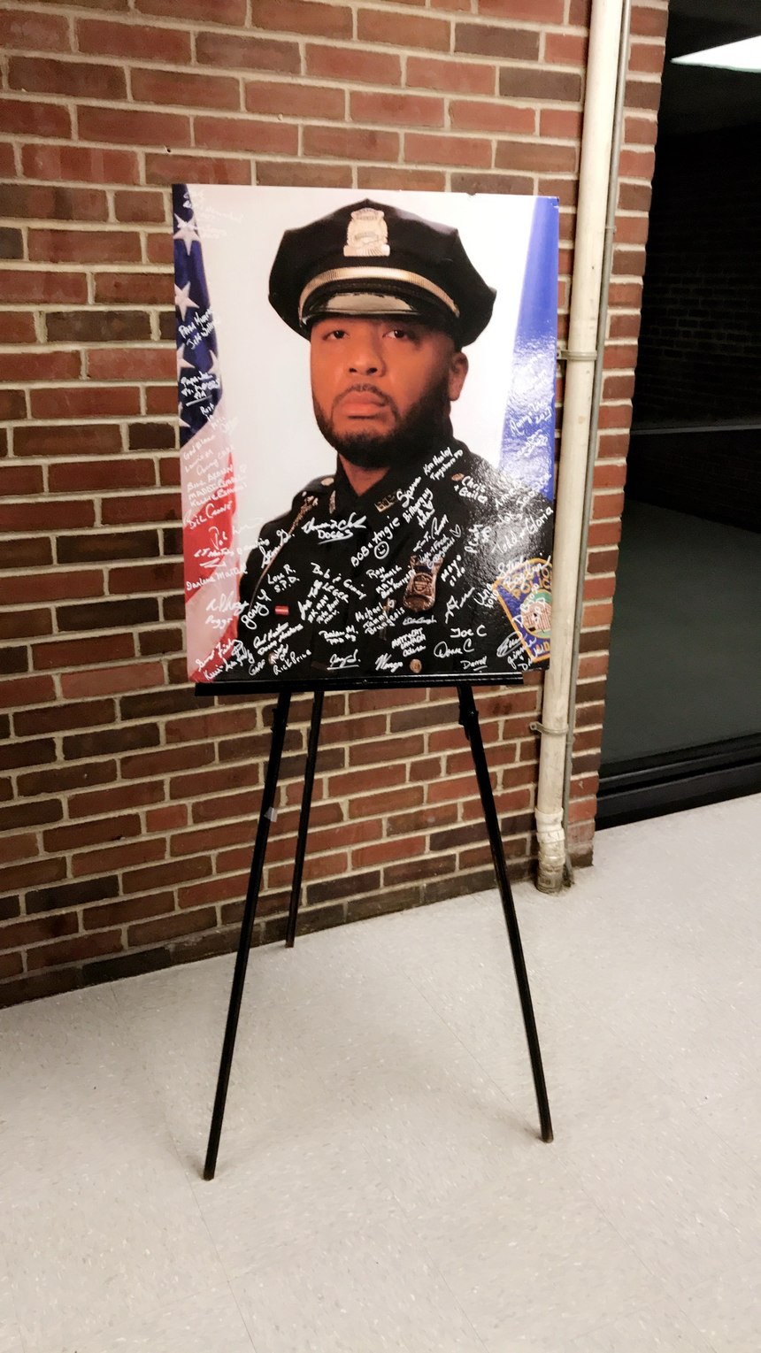 At a memorial ceremony, signatures cover an image of D.J.