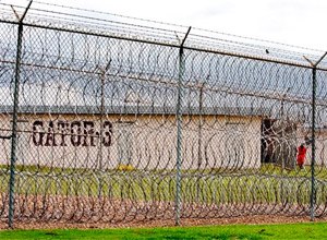 This April 22, 2009, file photo, shows a prisoner, far right, seen behind layers of wire razor fencing at the Louisiana State Penitentiary at Angola, La. (AP Photo/Judi Bottoni, File)