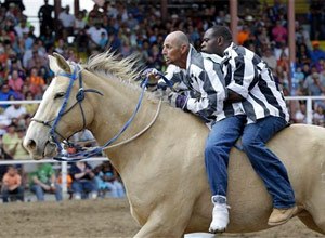 Inmates ride a horse in the Buddy Pick-Up event at the Angola Prison Rodeo in Angola, La., Saturday, April 26, 2014.