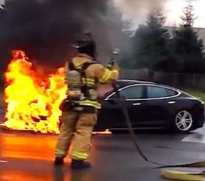 A screenshot from a YouTube video shows a Tesla Model S on fire as a result of a battery fire.