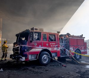 Firefighters look at the their Fire Engine 17 which burned in a massive pallet fire under the I-10 Freeway overpass at the 1700 block of East 14th Street on Saturday, Nov. 11, 2023, in Los Angeles.