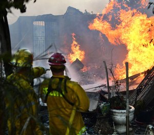 Firefighters put out flames still burning from the South Fire which swept through Lytle Creek, California near Cajon Pass on August 25, 2021 damaging at least six homes and threatening a hundred.