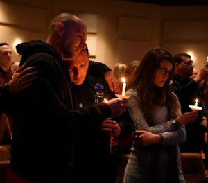 Elizabeth police officer Sean Bigler, middle, gets a hug from a fellow officer during a candle light vigil for their friend and fellow officer Douglas County deputy Zackari Parrish at Mission Hills Church in Littleton, Colo., Monday, Jan. 1, 2018.
