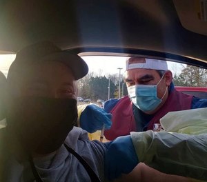Orange County EMT John Herrera administers a COVID-19 vaccine to New Hope Fire Chief Charles Bowden. North Carolina is boosting its vaccine workforce by temporarily allowing EMTs to administer the shots.