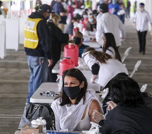A woman receives a COVID-19 vaccine from a nurse at a vaccination site run by Foothill Transit in Covina, California. Transit agencies across the country are giving free rides to vaccine sites and some are hosting clinics in their facilities.