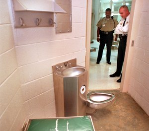 Two officers at the Mecklenburg County Detention Center in Charlotte, North Carolina, look into a cell. More than a third of jobs at the facility are currently vacant.