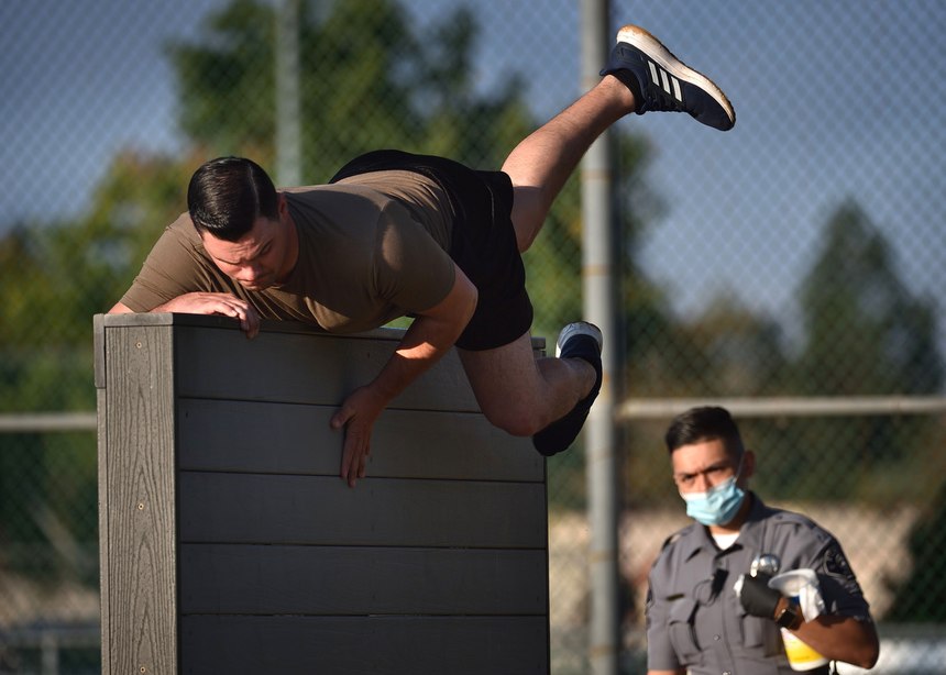 Recruit applicants jump a six-foot wall during Tustin Police Department's physical agility test in November 2020.