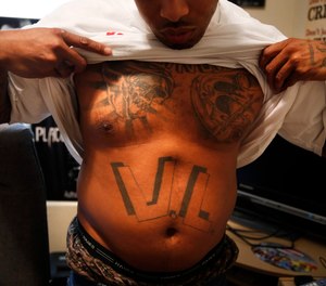 A former inmate displays the Vice Lords tattoo on his stomach.