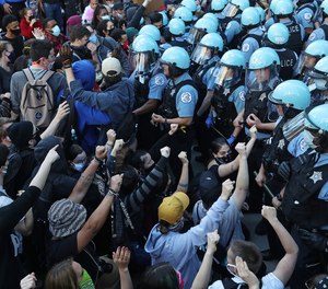 Police officers hold back protesters May 30, 2020, in Chicago during a rally to remember the killing of George Floyd