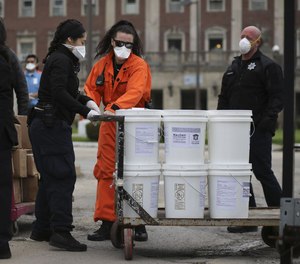 Stateville Correctional Center personnel pull carts of hand sanitizer and bars of soap on April 24, 2020.