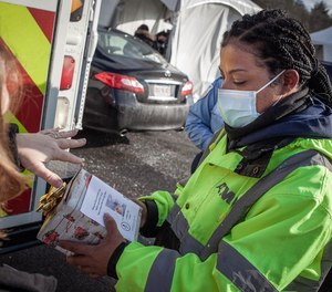 East Longmeadow High School Music Teacher Carol Forward presents a thank-you give to American Medical Response EMT Jessica Wright, one of the AMR staff members who has been testing thousands of people for COVID-19 in Springfield, Mass.