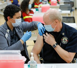 Franklin County assistant health commissioner Alexandria Jones gives a COVID-19 vaccine to New Albany Plain Township fire chief Jack Rupp on Monday, Dec. 28, 2020.