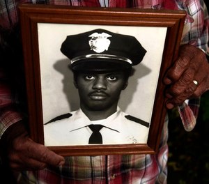 Nate Howard holds a photograph of Wallie Howard Jr. taken after Wally became a police officer. Howard is Wallie's uncle.