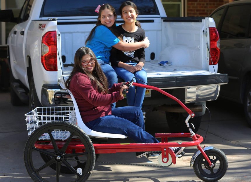 Middle school student Grace Holguin, 14, on her special needs trike, and her sisters Eve, 9, and Sophia, 10.