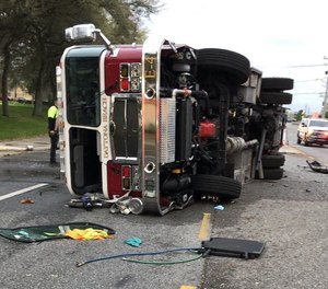 Police say a fire apparatus was flipped to its side when it was rear-ended by another vehicle Saturday. Five firefighters were injured and the driver of the other vehicle was killed.