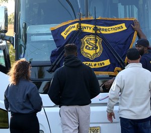 Members from PBA Local 199 Union County Corrections hang their banner on the front of a bus at a rally for COs in nearby Cumberland County, who were facing a similar proposal, with accompanying layoffs, last year.